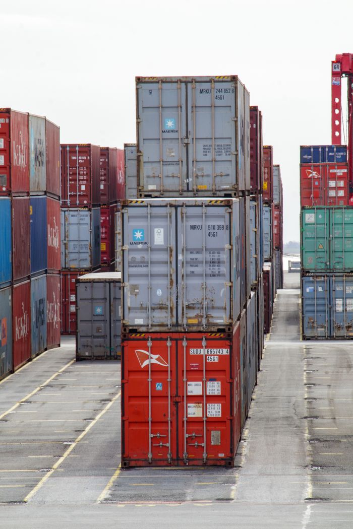 About Vertical shot of colorful shipping containers stacked at an industrial port, showcasing logistics.