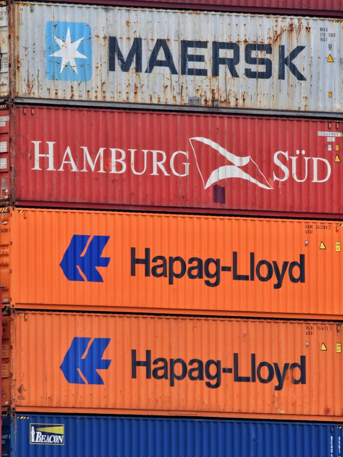 Services Close-up of stacked shipping containers featuring Maersk, Hamburg Süd, and Hapag-Lloyd logos.